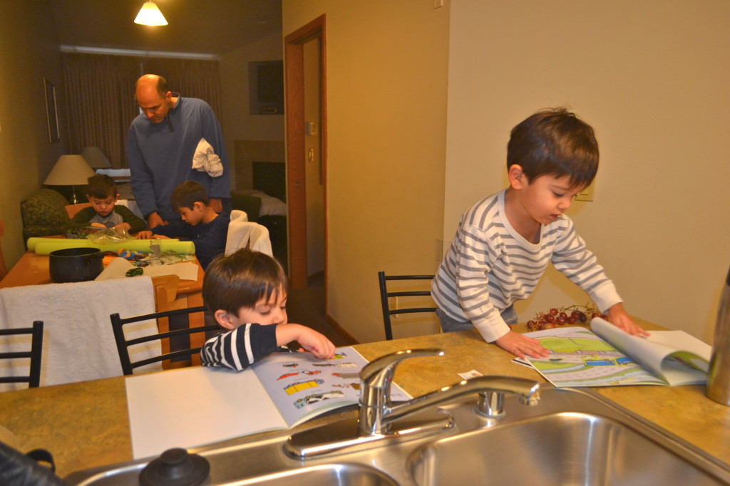 Twins playing with their new sticker books from Hanukkah while the older boys do a new puzzle with Adam.